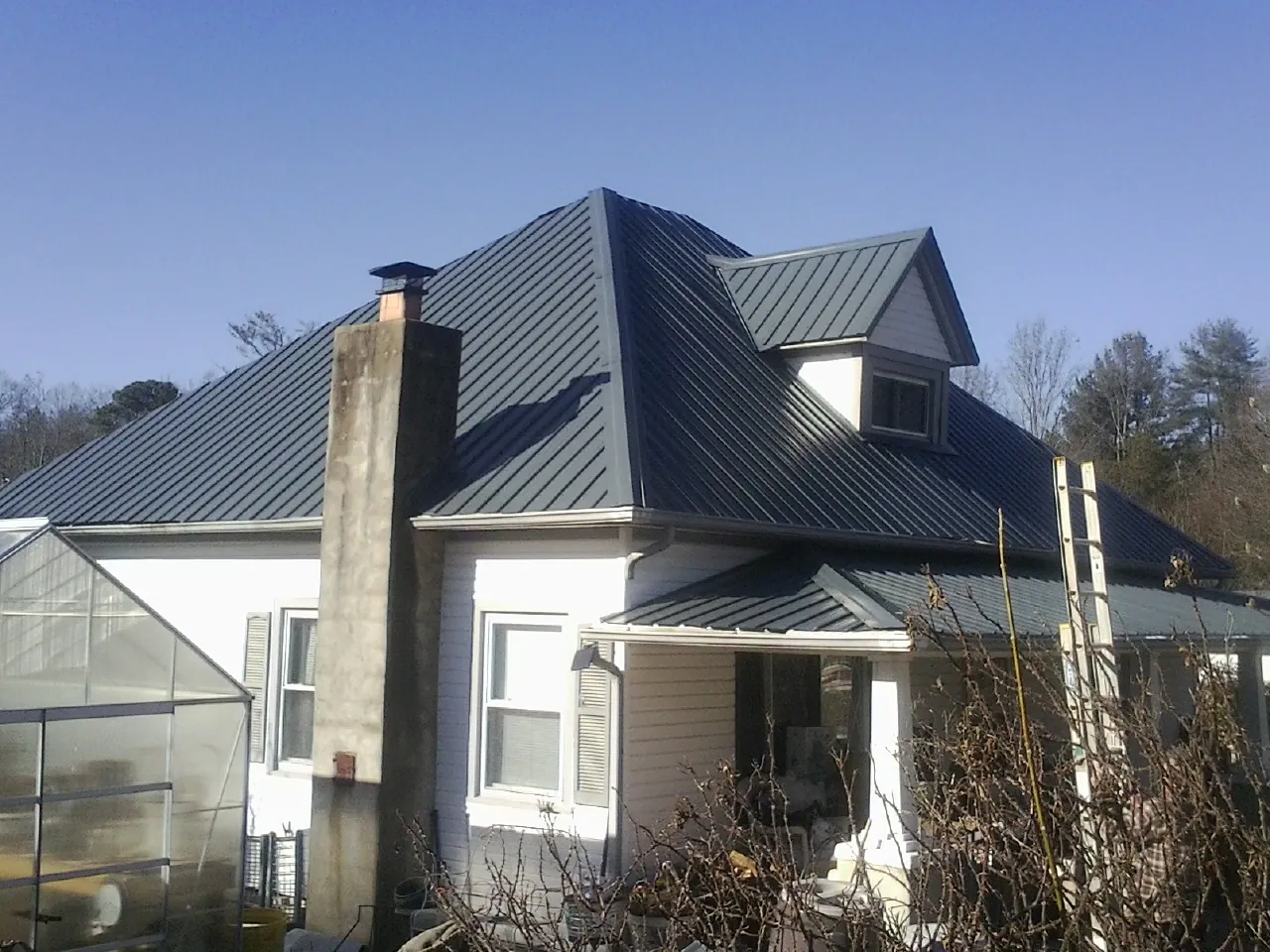 Dark blue standing seam metal roof on a white farmhouse with dormer — Slate & Tile Roof Repair by Roofing Brothers in East Hartland