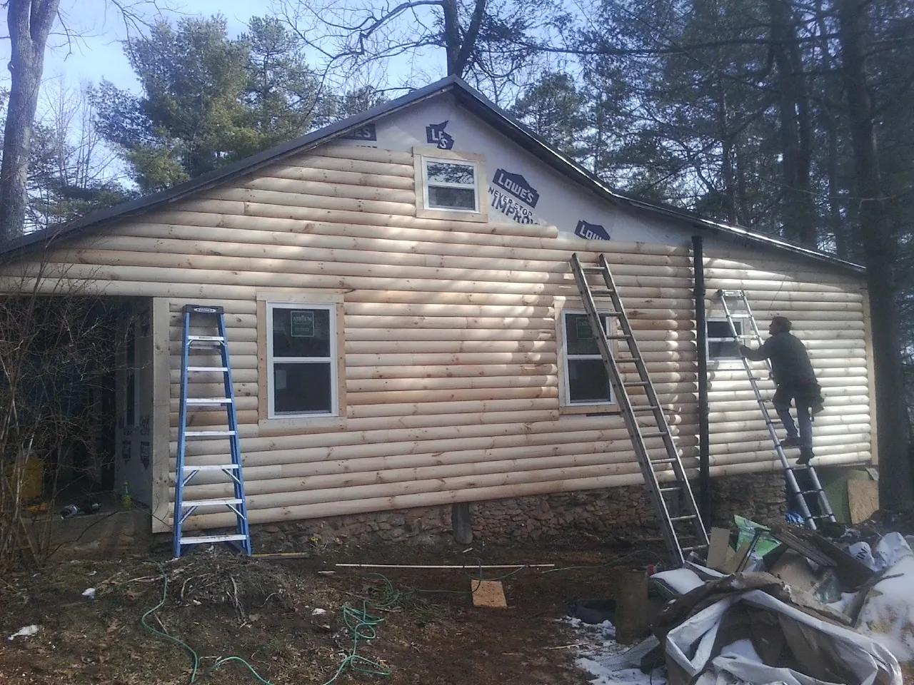 Ladders set against fresh log siding during an exterior remodel in East Hartland