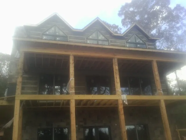 Dormers and porch framing on a large log home under construction — Roof Coating work by our crew in East Hartland