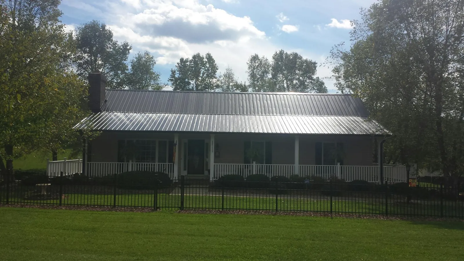 Gray metal roof on a brick ranch with a full width front porch — Gutter Guard Installation work by our crew in East Hartland