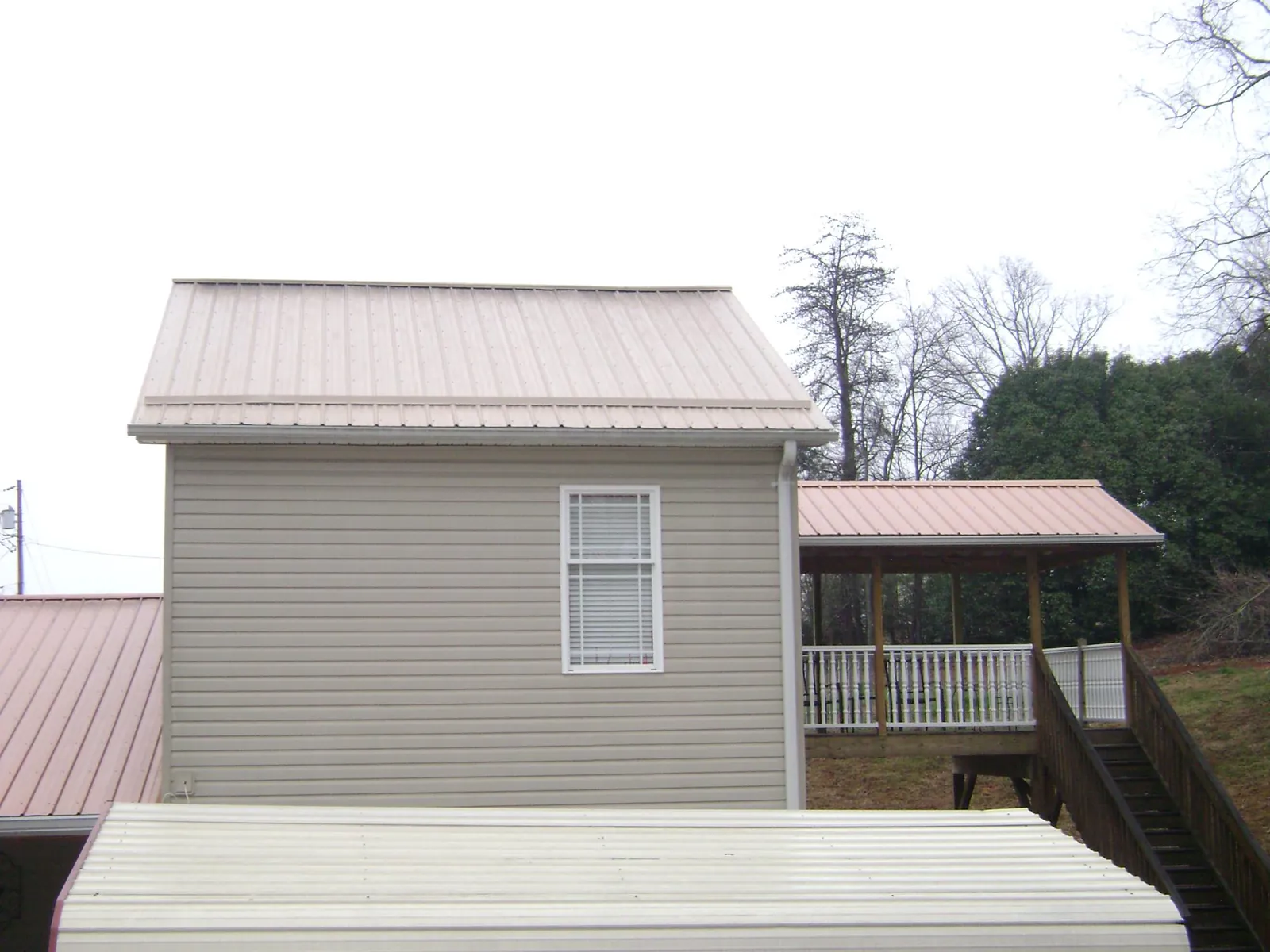 Tan metal roofs on a two story addition and attached porch, from a Roof Replacement job in East Hartland