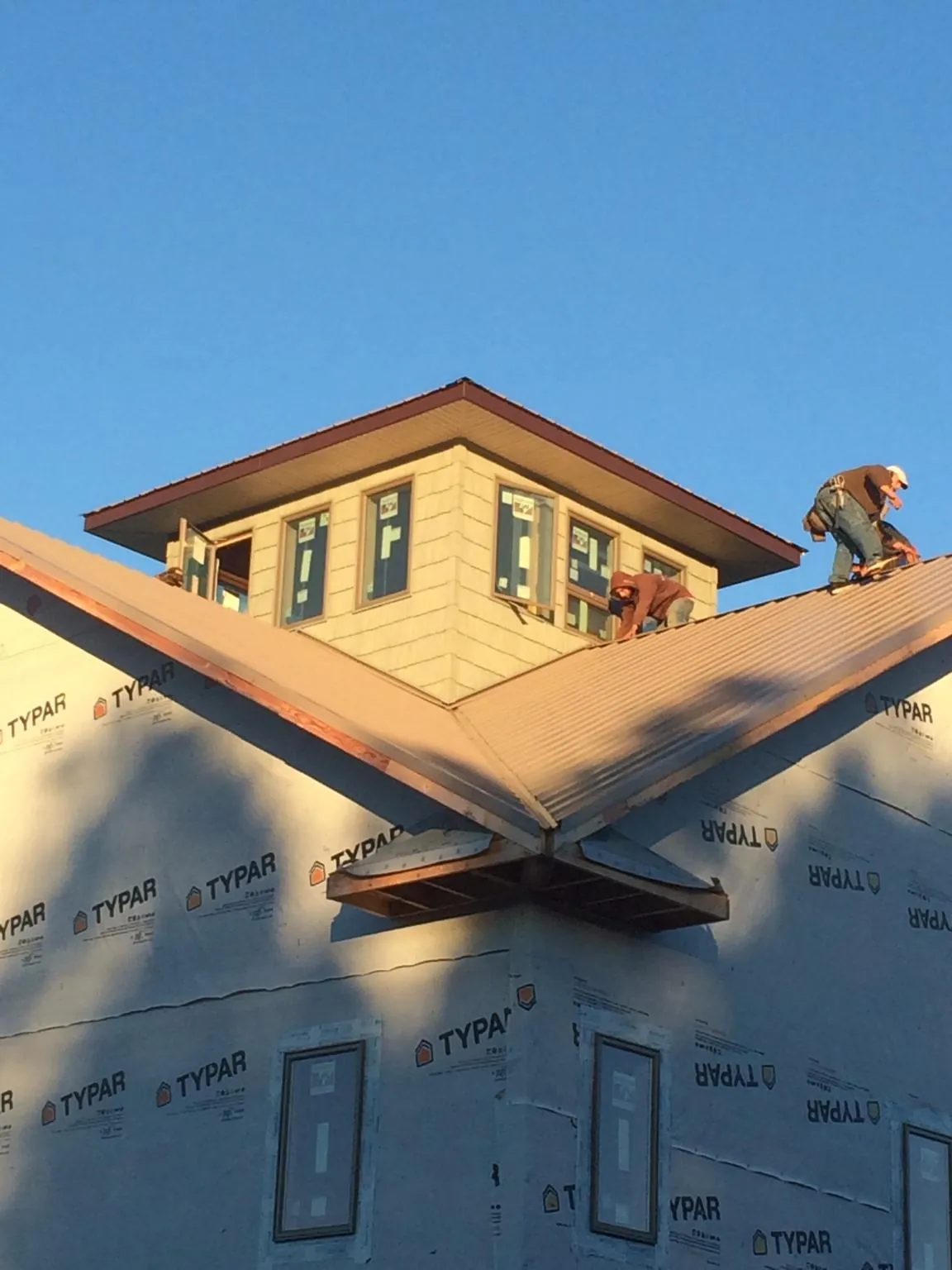 Roofers working around a rooftop cupola on a new metal roof at sunset — Roof Waterproofing in East Hartland by Roofing Brothers